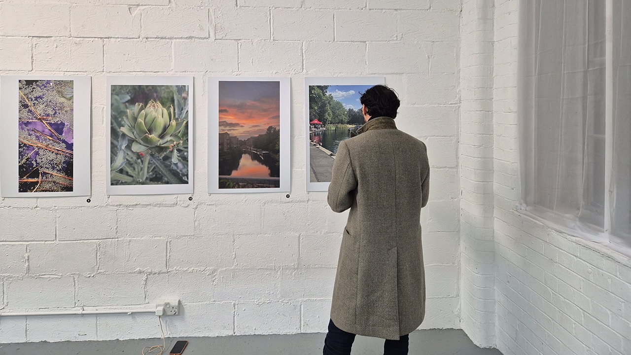 A man standing in front of a wall display of photographs